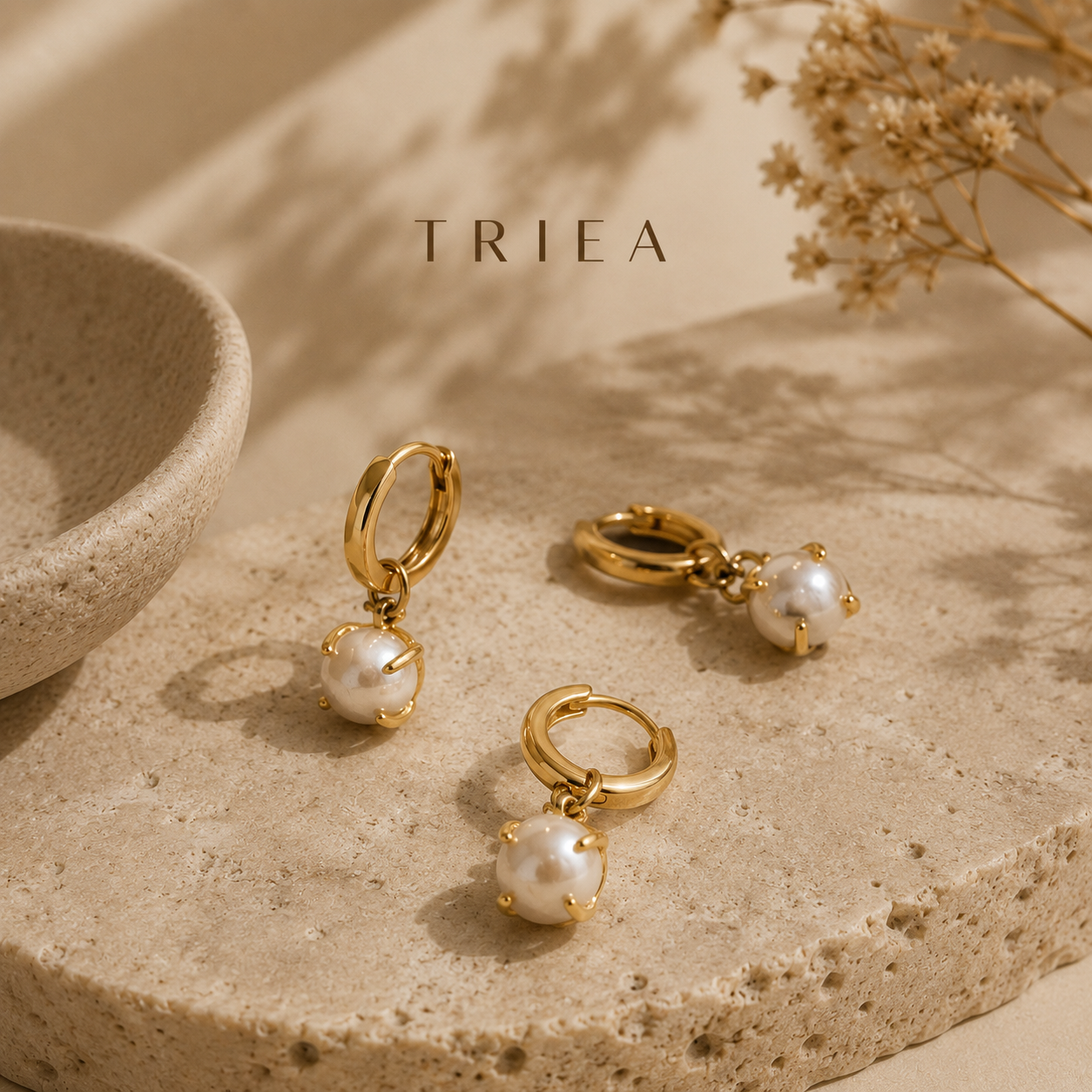 Three TRIÉA pearl earrings styled in warm natural light